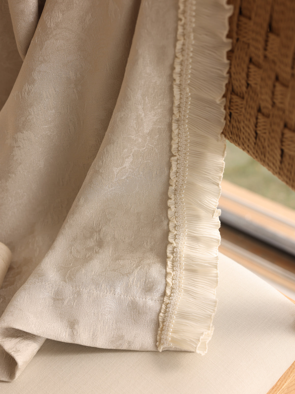 Close-up of warm beige chenille curtain texture and ivory ruffle edging