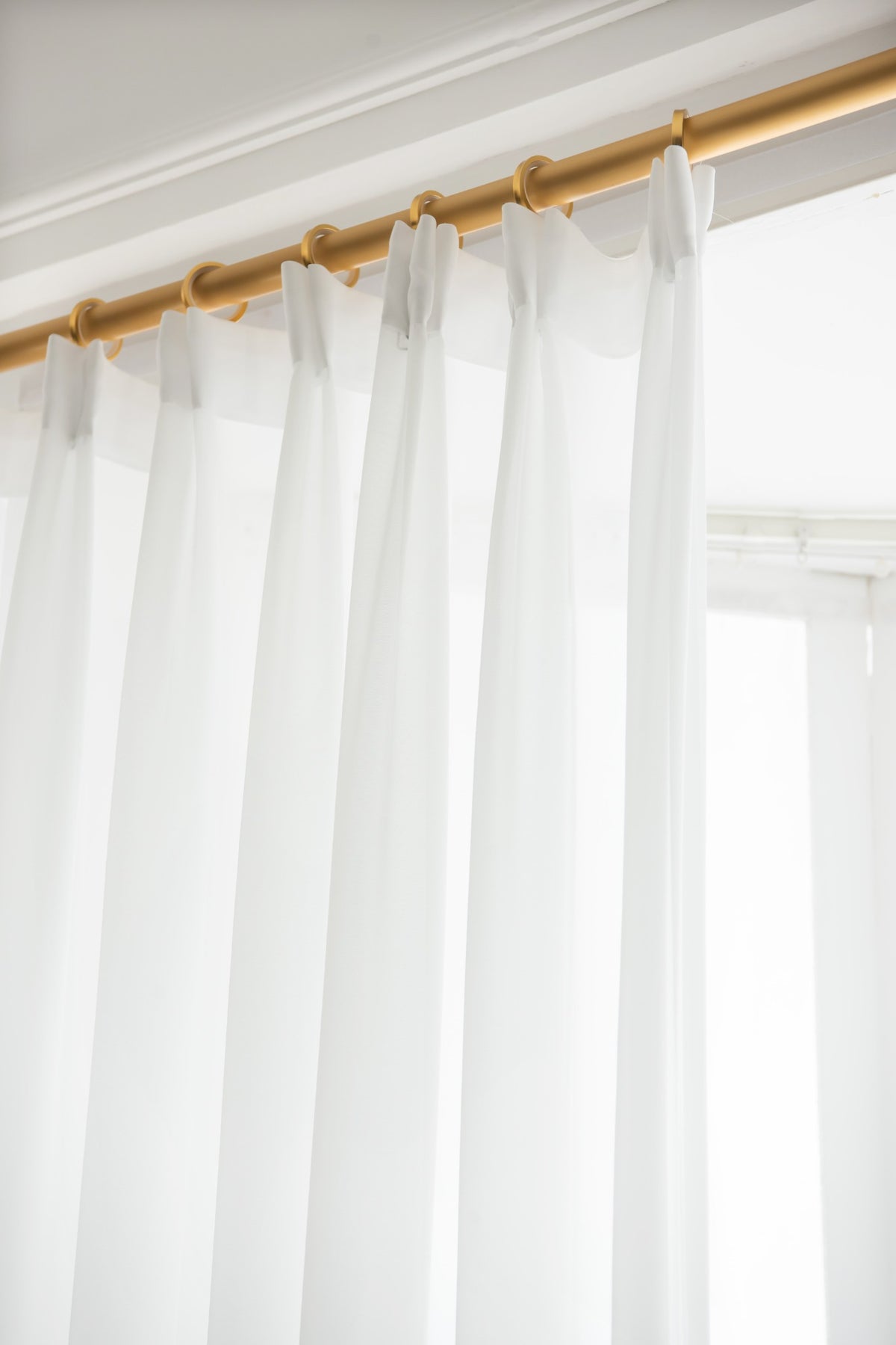Close-up of the neat heading and smooth pleats on a white sheer curtain