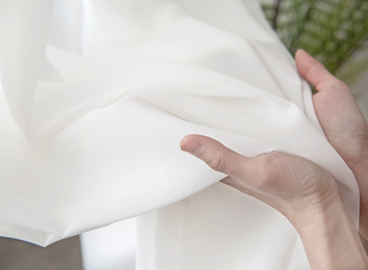 Hand-held close-up showing the soft drape of white diamond mesh sheer fabric