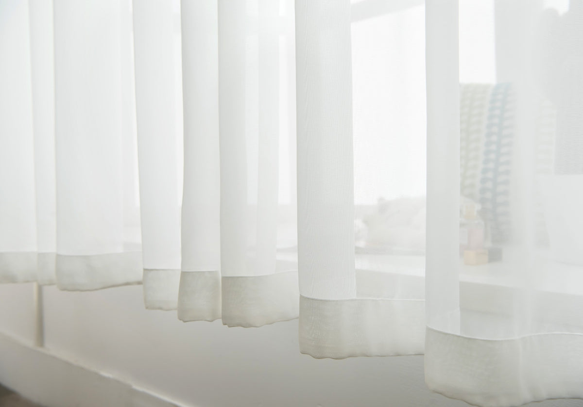 Clean finished hem and floor-length drape of a white sheer curtain