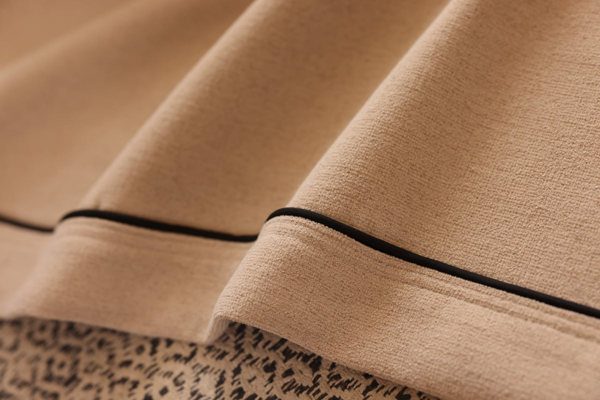 Close-up of slim black piping on warm beige chenille curtain